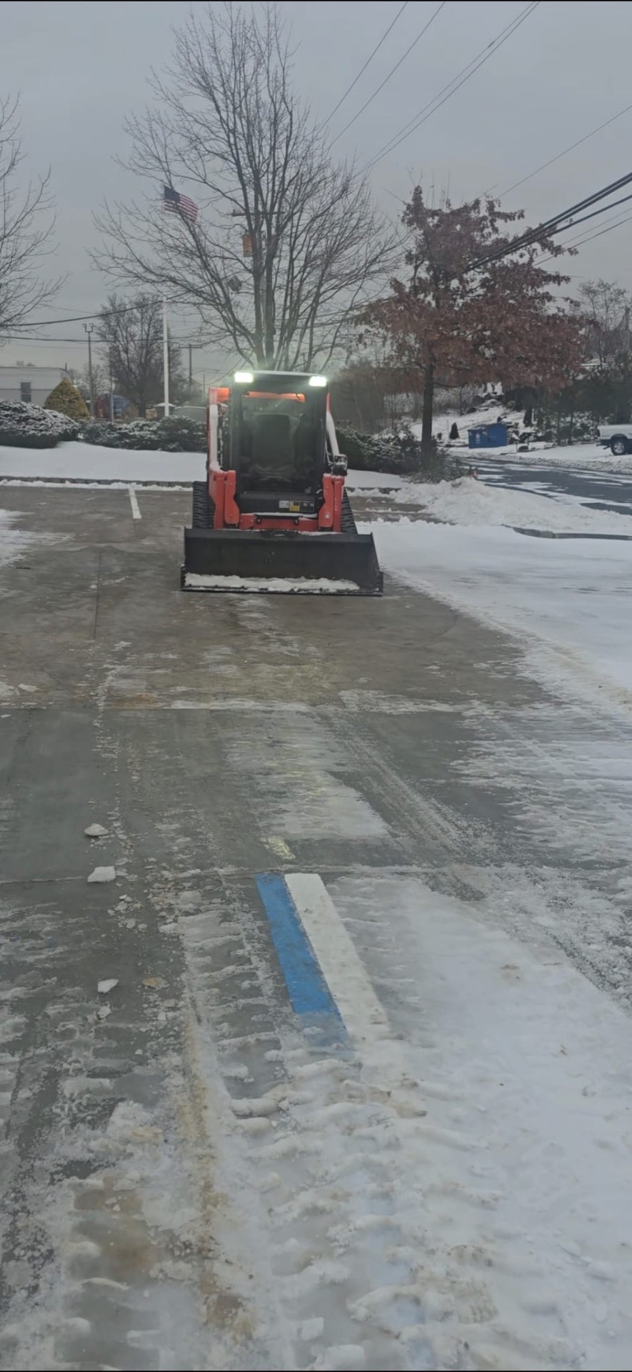 Bobcat clearing snow from parking lot